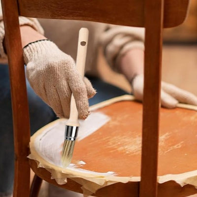 charpentier peignant une chaise avec le pinceau rechampir