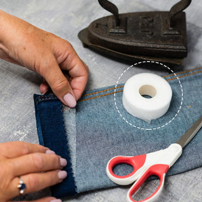 jeanne effectuant retouche ruban adhesif ourlet sur jeans